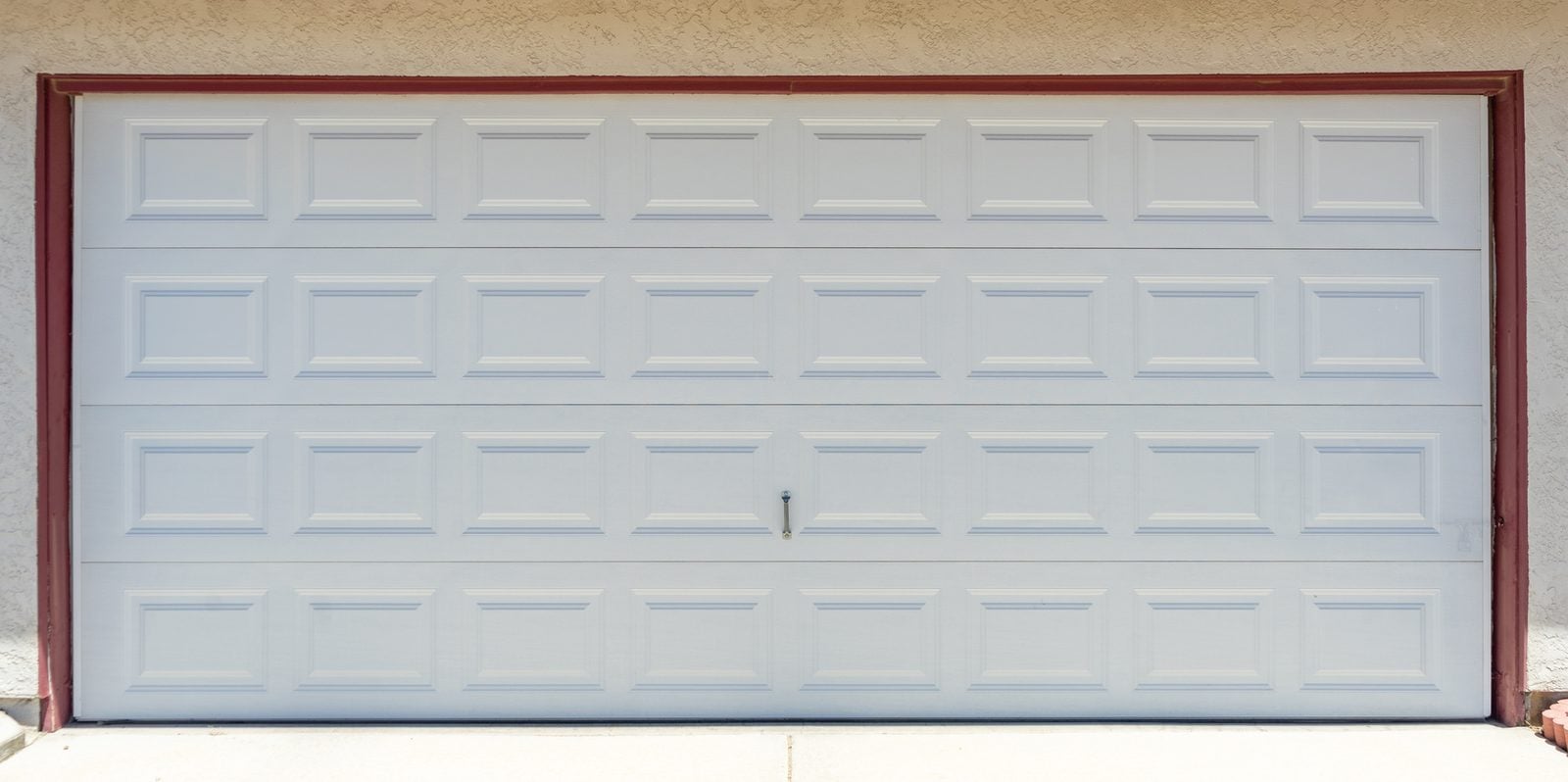 Wide white raised-panel garage door on a suburban house